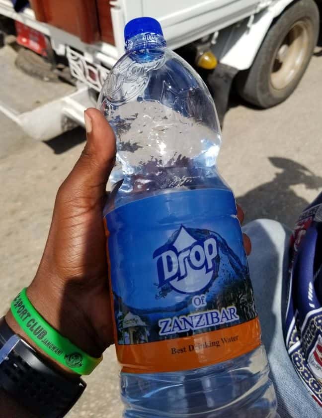 A man's hand holding a water bottle of Drop of Zanzibar drinking water. Zanzibar's best bottled water 